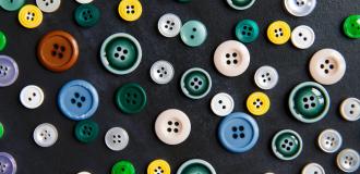 An assortment of buttons of different colours and sizes on a black background.