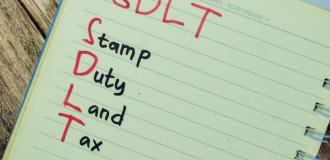 Notepad on a table with the letters "SDLT" which stand for Stamp Duty Land Tax