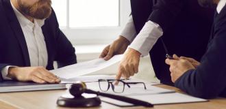 business people sat at desk pointing at paper