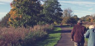 two elderly people walking in a field 