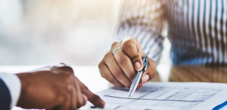 close up of the hands of two people reviewing a contract