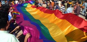 A photo of a long rainbow flag being carried by many people in Hyderabad, India