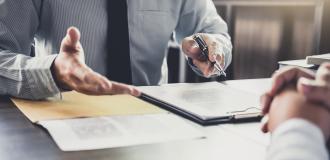 A person explaining documents on a table to another person