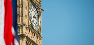 Big Ben against a clear blue sky with a union flag in the left corner