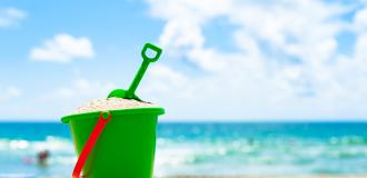 A green bucket and spade at the beach.