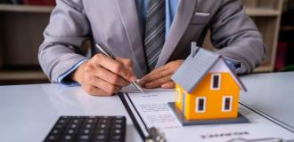 Man signing document with yellow house statue 