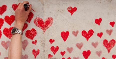 Person putting a red heart on a concrete wall