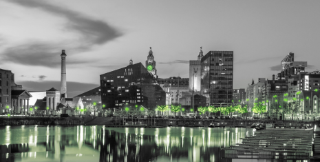 Black-and-white photo of a city at night with selective green lights on buildings and streets, creating a dramatic, modern mood.