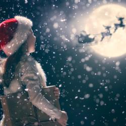 child at christmas looks at sleigh passing the moon 