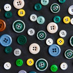 An assortment of buttons of different colours and sizes on a black background.