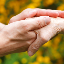 A white person holding another white person's hand with both hands in a caring way.