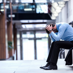 A man sits on a bench with his head in his hands.