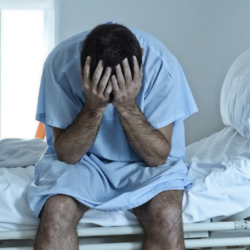 Man in hospital holding head in hands