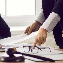 business people sat at desk pointing at paper