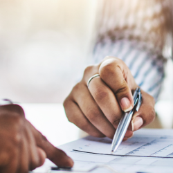 close up of the hands of two people reviewing a contract