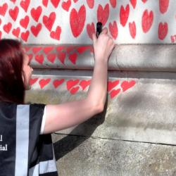 girl writing on covid 19 memorial wall