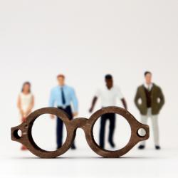 Various miniature figures only partially seen through a pair of glasses. 