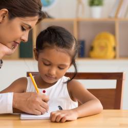 A woman helps her child with her homework.