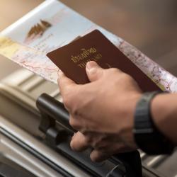 A hand holding a passport and other documents.