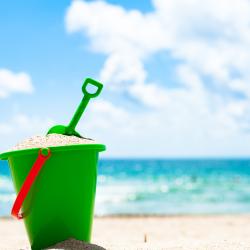 A green bucket and spade at the beach.