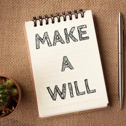 A photo of 'make a will' scribbled on a notepad next to a pen and a cactus.