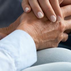 two people dressed in blue sit together holding hands. They are comforting and supporting one another