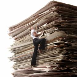 A woman climbing an enormous stack of papers.