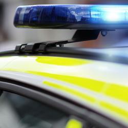 a close up of a British police car with blue flashing lights. 