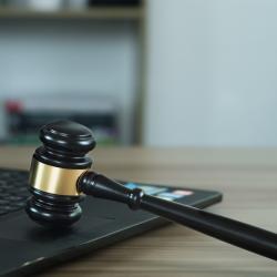 A Judge's gavel resting on the keyboard of a grey laptop.