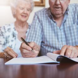 An elderly couple signing a piece of paper together