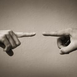 two hands point at each other symbolic of blame 